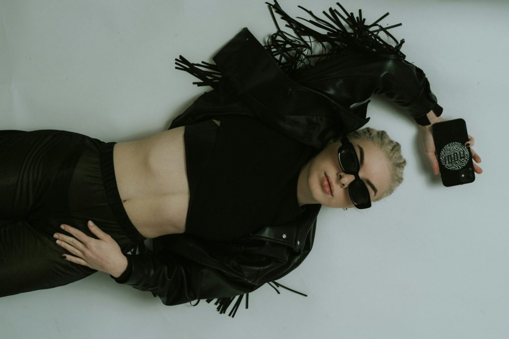 eine Frau in einem Lederoutfit und einer Sonnenbrille liegt auf dem Boden